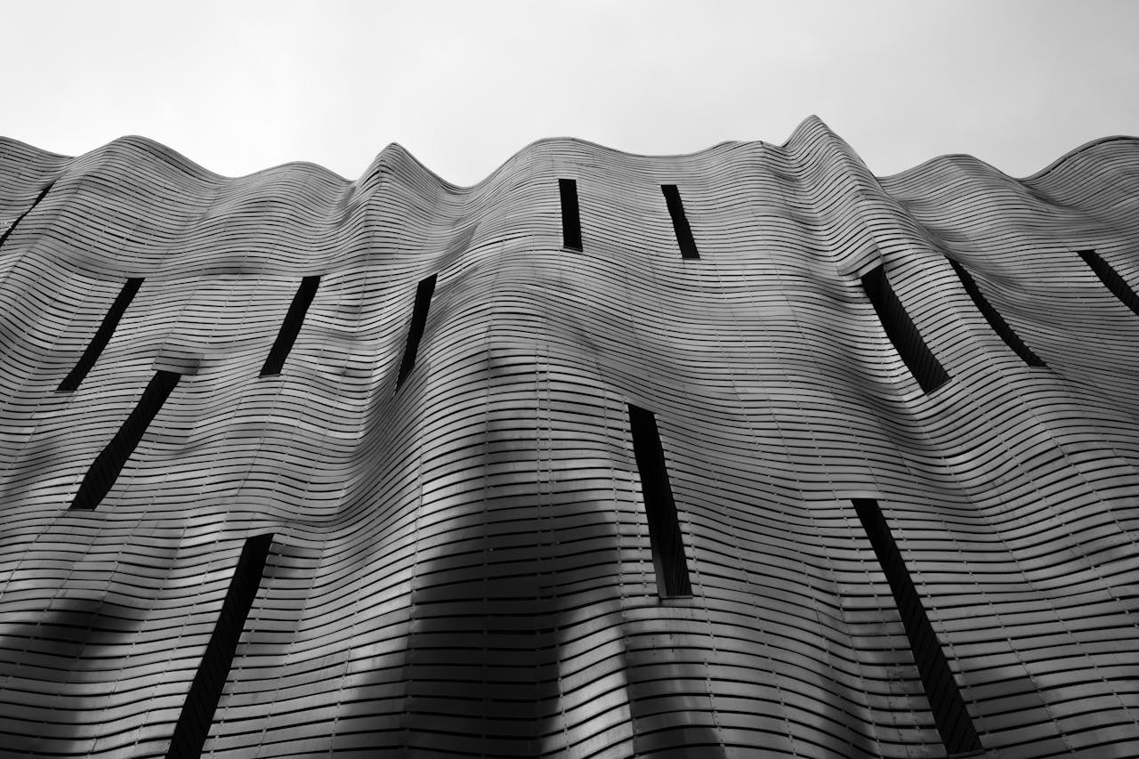 Black and white photo of a wave-like modern building facade with vertical slits.