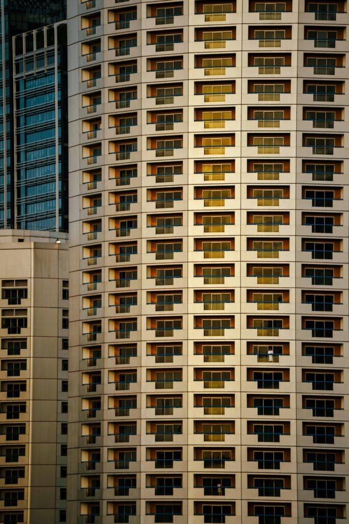 Vertical shot of a modern high-rise building with reflective windows in warm lighting.
